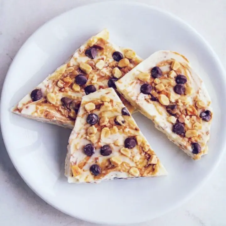 Three slices of Keto Peanut Butter Yogurt Bark topped with chocolate chips and crushed peanuts.