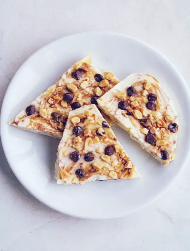 Three slices of Keto Peanut Butter Yogurt Bark topped with chocolate chips and crushed peanuts.