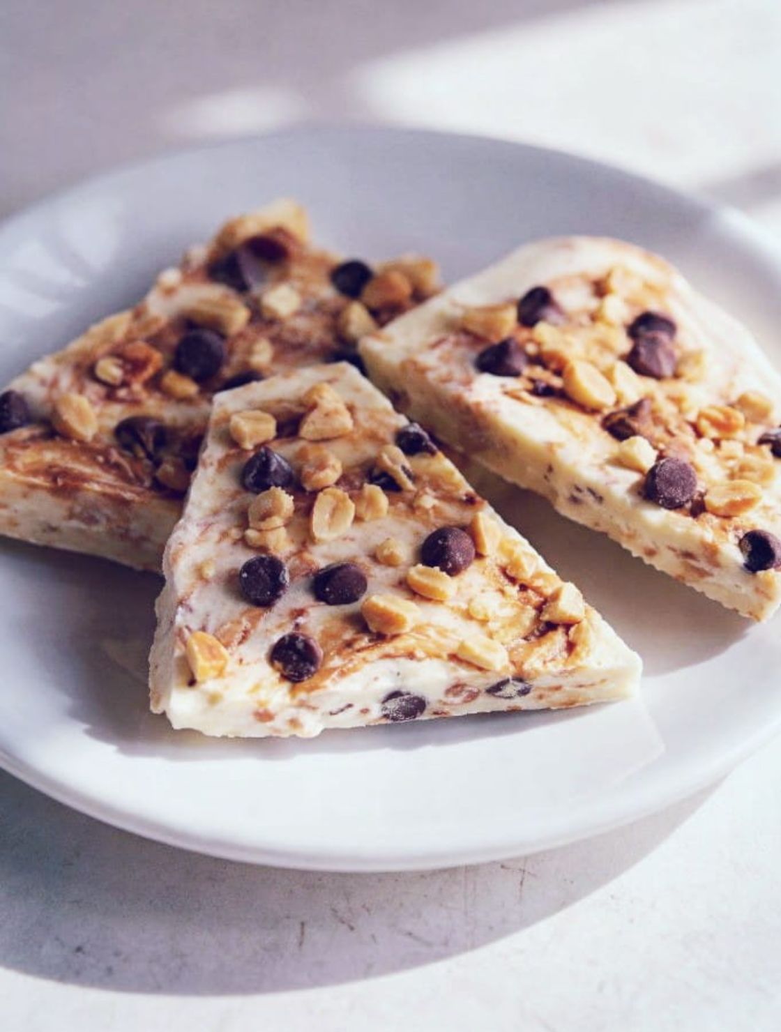 A healthy low carb snack featuring frozen Keto Peanut Butter Yogurt Bark on a white plate.