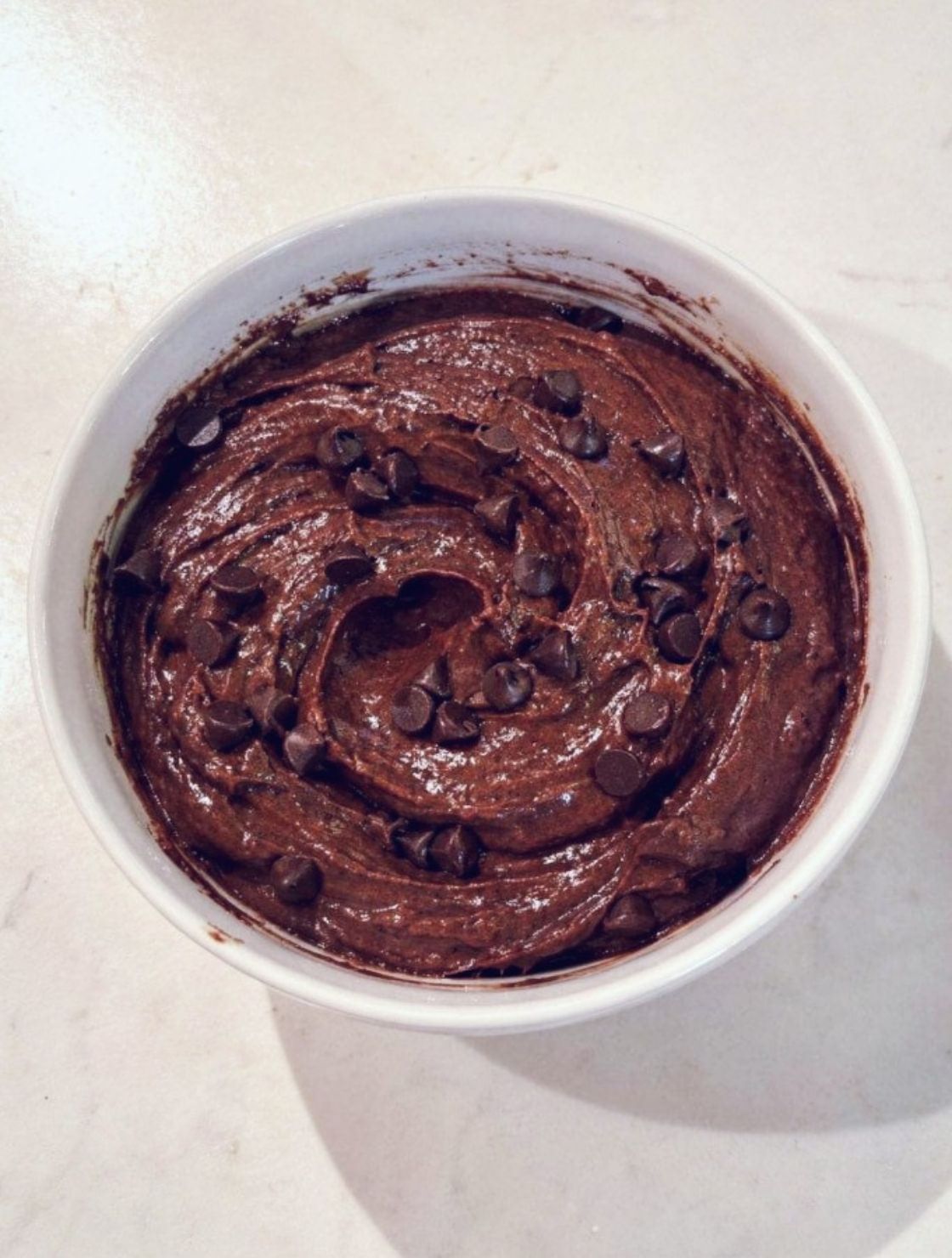 Protein Brownie Batter Dip in a white bowl topped with mini chocolate chips, rich high-protein chocolate dessert with a creamy fudgy texture.